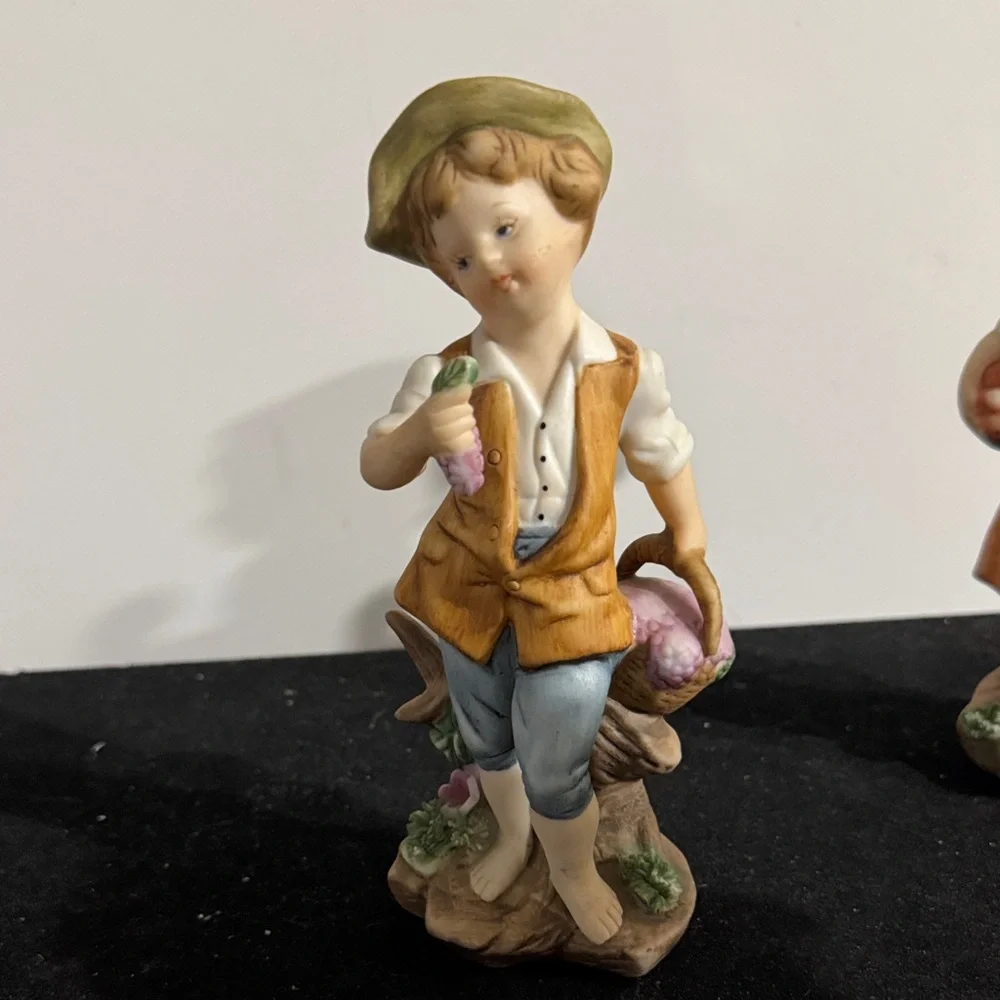 vintage hand-painted porcelain figurines of a boy and girl carrying baskets.